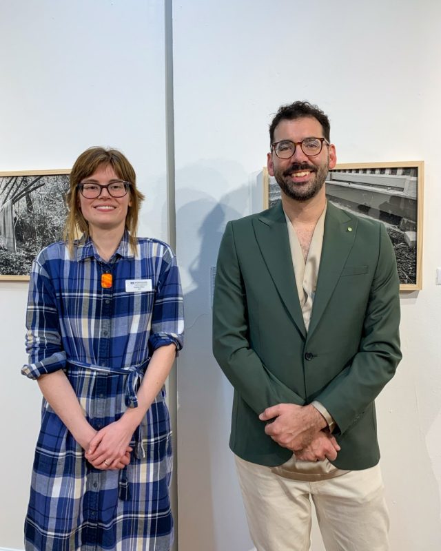woman and man standing in front of framed phtogoraphy in a gallery