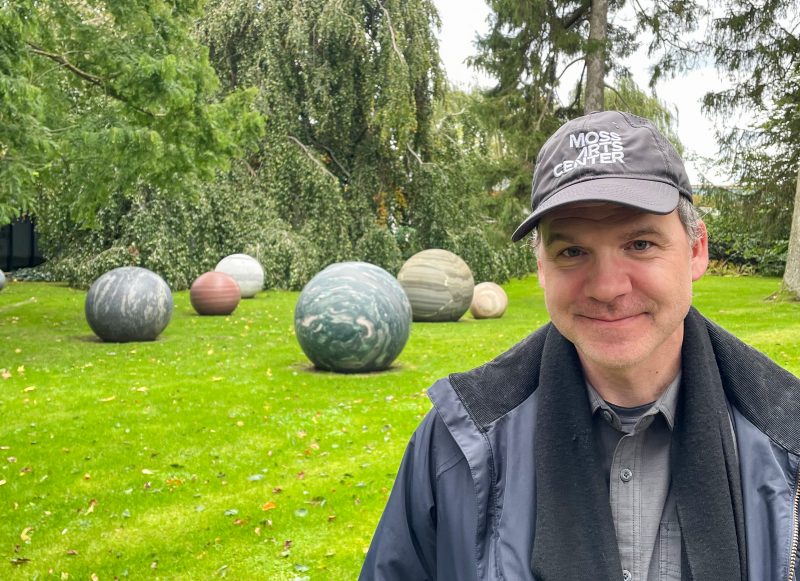 Brian Holcombe standing in front of several orb-like outdoor scupltures