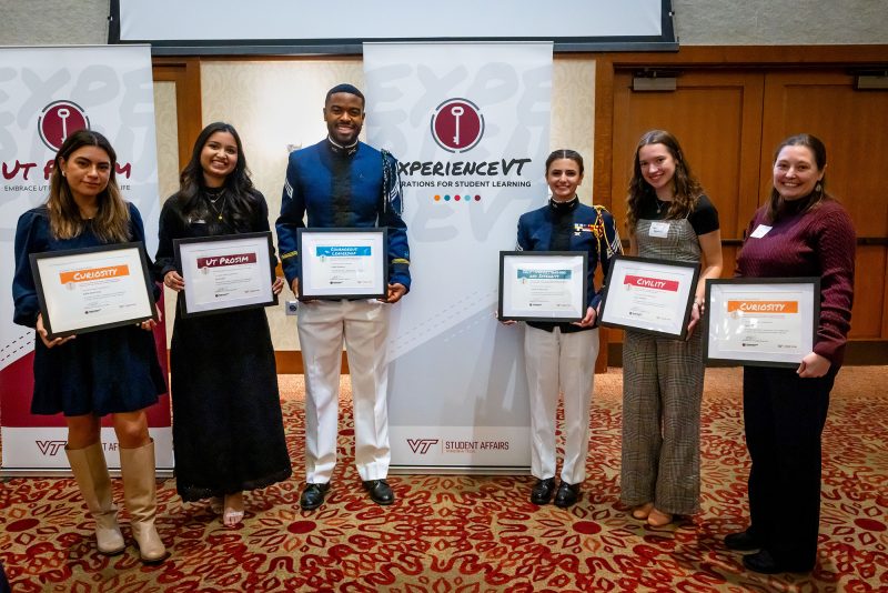 Five students and one faculty member pose with their framed certificates at the Inn at Virginia Tech.