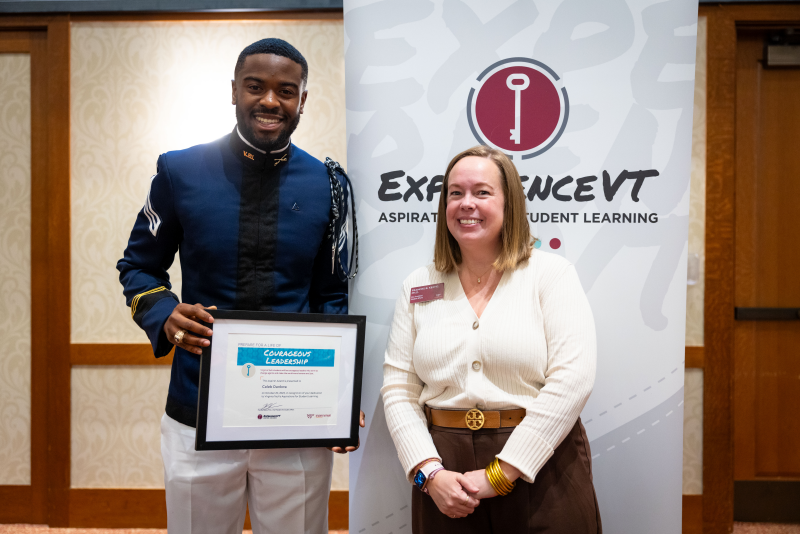 Caleb stands to the left of Vice President for Student Affairs, Frances Keene, holding his award.
