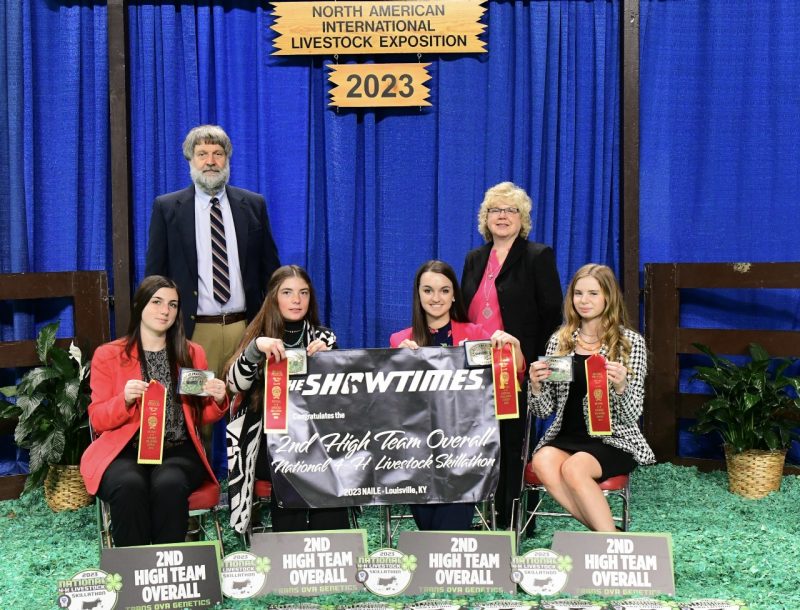 Virginia's second-place national 4-H Skillathon team sits holding their awards, with coaches in the background.