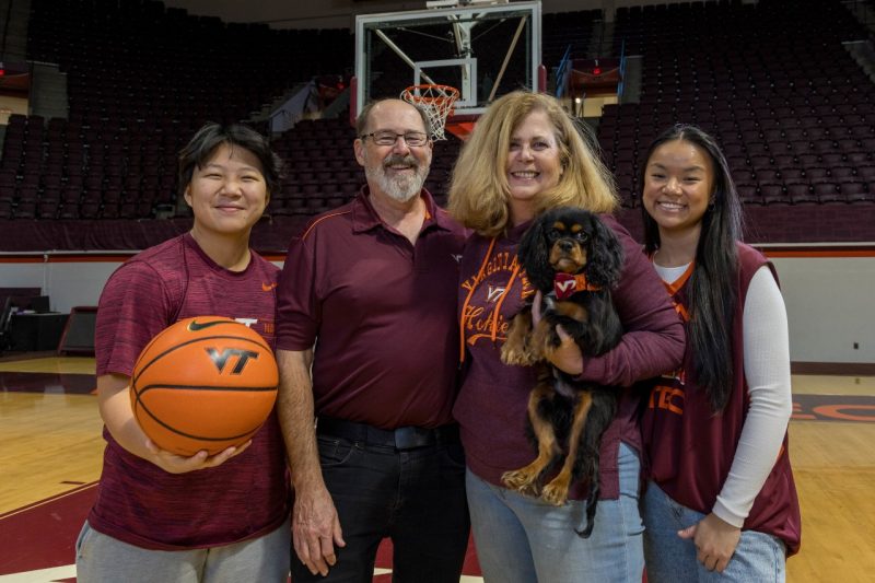 Group of people in Hokie gear posing on the basketball court.