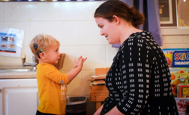 Bennett, 2, extends his clean hands to Margaret after using the sink in the classroom.