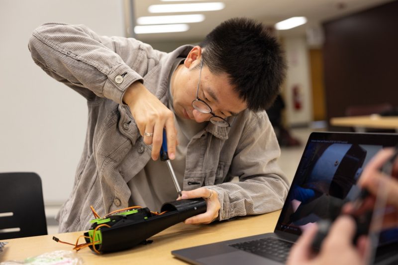 a student uses a screw driver to build his robot