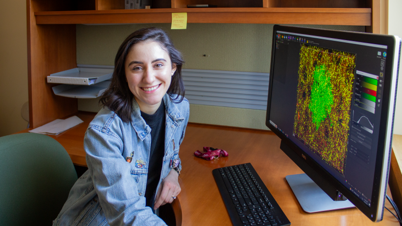 This photo shows Beatriz in front of a computer screen that shows an astrocyte.
