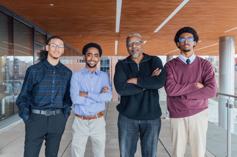 Professor of Engineering Wayne Scales stands with three Black male students who participated in the symposium named for him.
