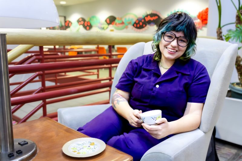 Beka Olson sitting in the Wallace Atrium and sipping tea.