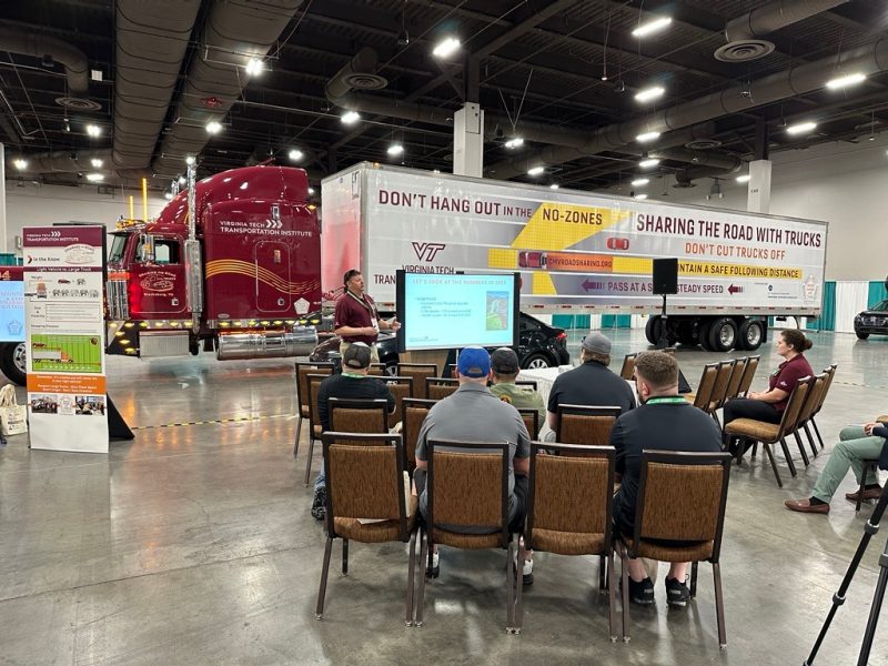A presentation in front of a semi-truck in a conference hall.
