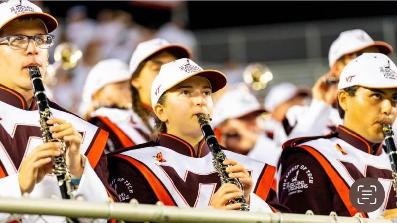 A group of Virginia Tech students dressed in marching band gear play various instruments during a performance.