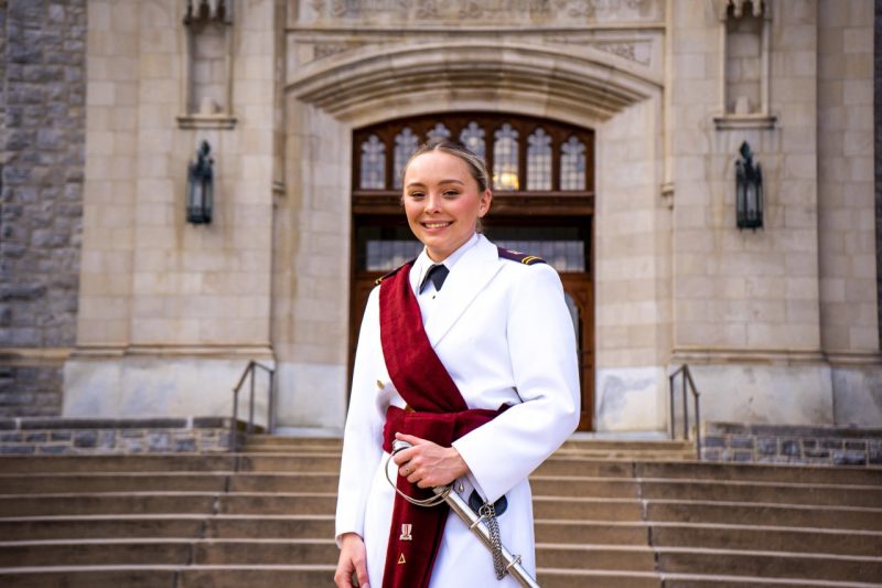 Stevens stands in her white dress uniform in front of the steps of Burruss Hall.