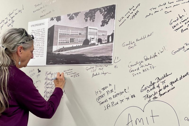 An alumna signs a wall in Randolph Hall with her memories.