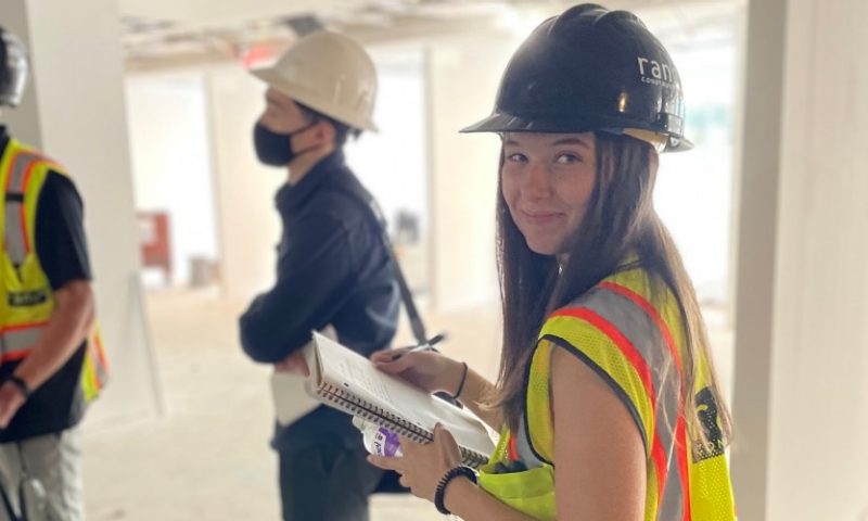 Woman smiles while in PPE on a construction job site.