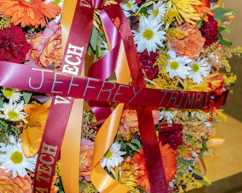 A colorful wreath has a maroon banner with Jeffrey Trimble's name on it. 