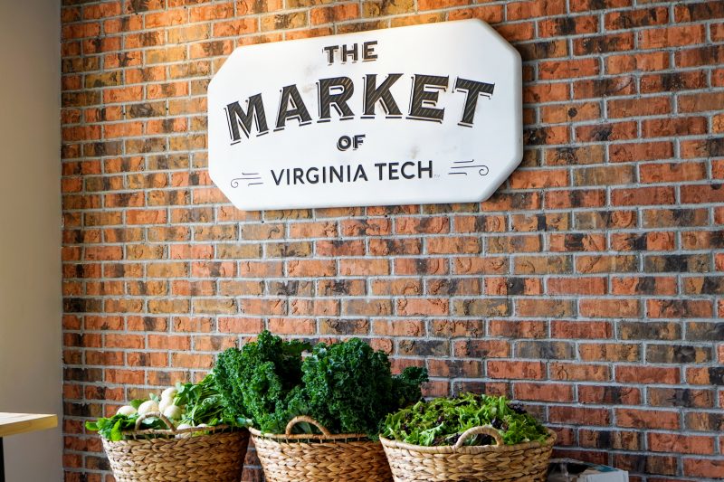 Baskets of vegetables sit on a table beneath a sign reading "The Market of Virginia Tech."