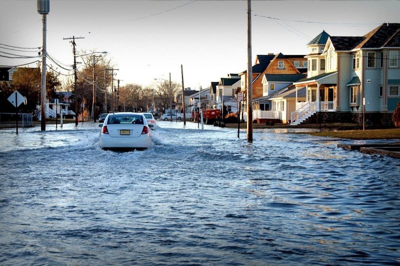 A car drives along a flooded road.