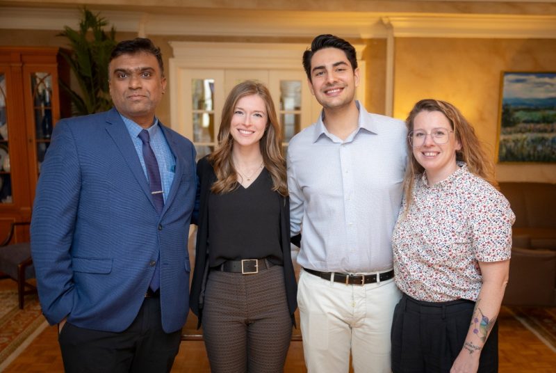 Four individuals standing side-by-side, two men, two women