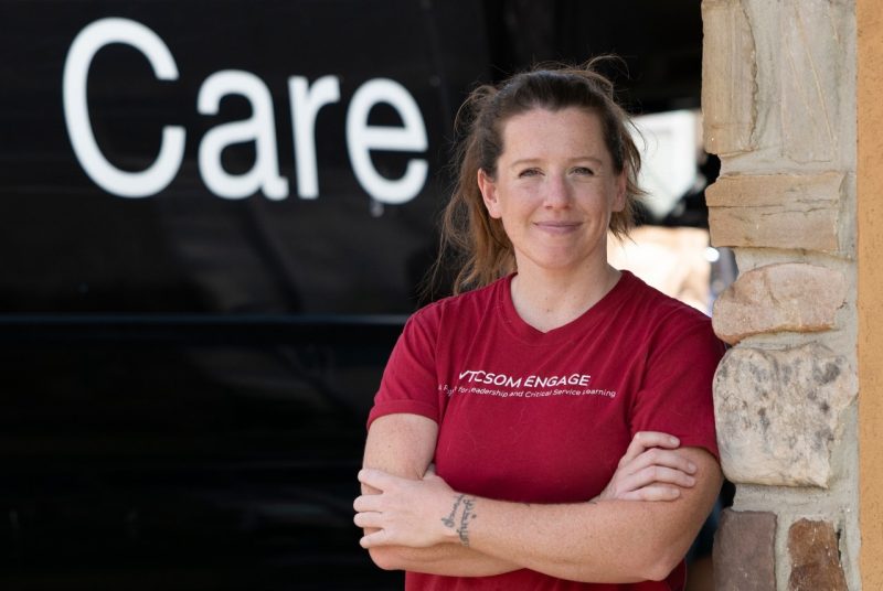 woman wearing VTCSOM Engage t-shirt standing out side a CARE van