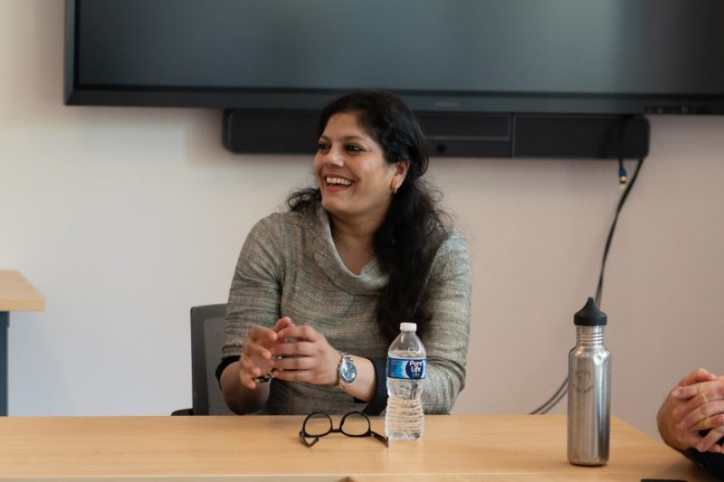 Woman sitting in conference room with others.