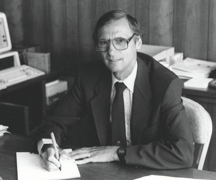 CNRE Hosner B&W A person sits at a desk.