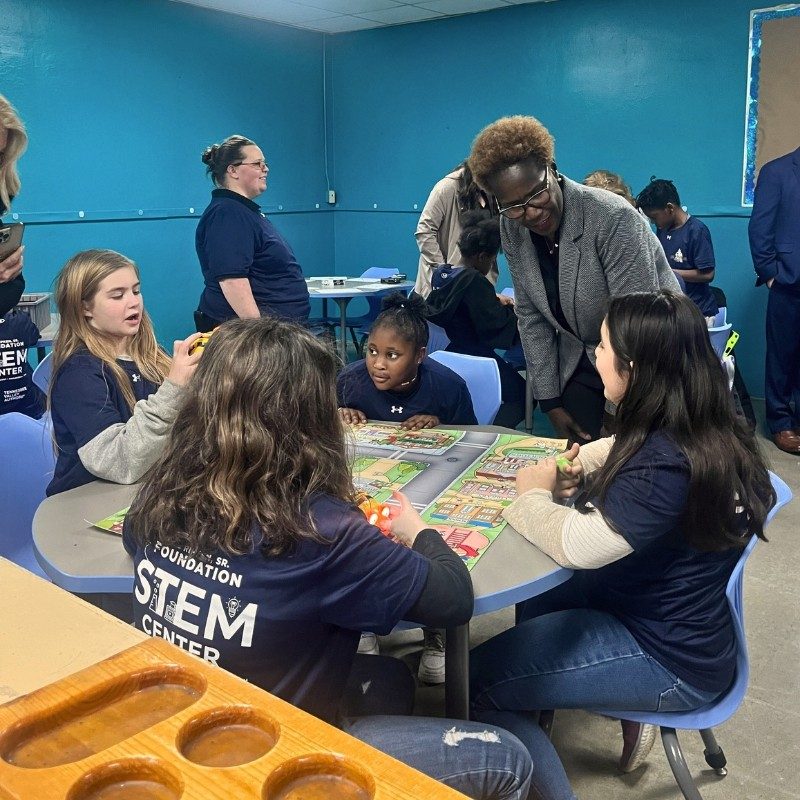 Jeannette Mills - STEM Center Opening - students Jeannette at the opening of a STEM Center in Knoxville. She is talking to group of four young girls all sitting around the table.