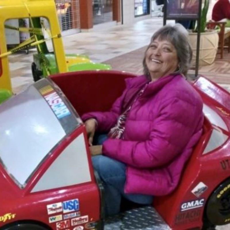 Photo of Genevia Dowdy smiling while sitting in a toy car
