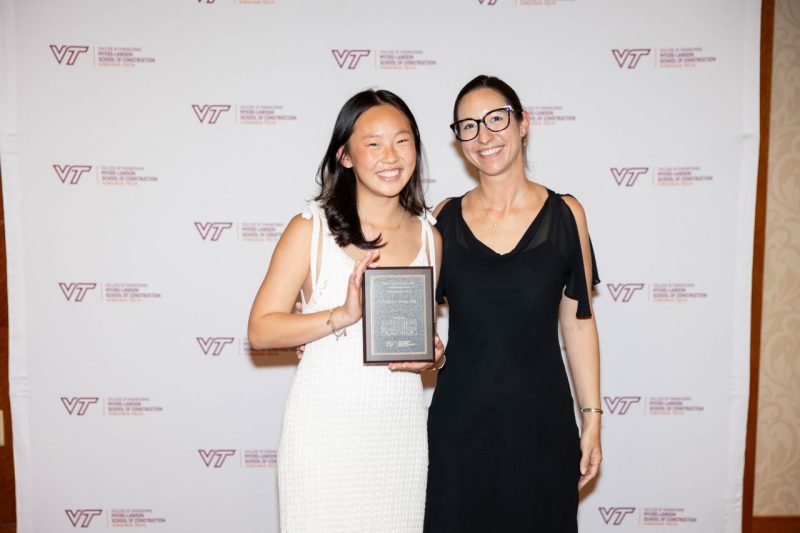 Woman at left holds an award while posing with woman at right.