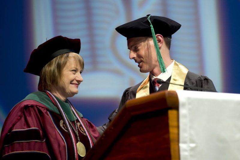 Dean Cynda Johnson (at right) greets Class of 2014 President Matt Joy at the podium at the charter class’ graduation ceremony.