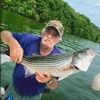 Ernie Hamilton holds a fish while standing in front of water