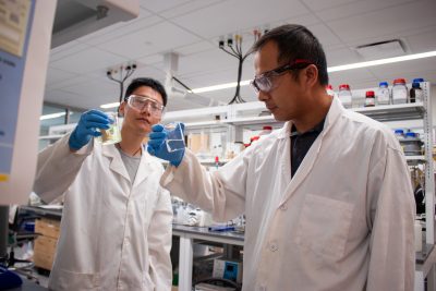 Two researchers comparing produced water before and after treatment in a lab.