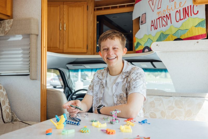 Claire Branscome sits at a table inside Virginia Tech's Mobile Autism Clinic, a converted RV, surrounded by fidget toys that can be helpful to autistic children.