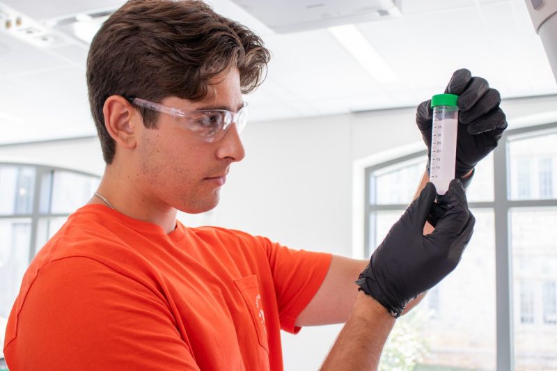 A student holding up a test tube inside a lab.