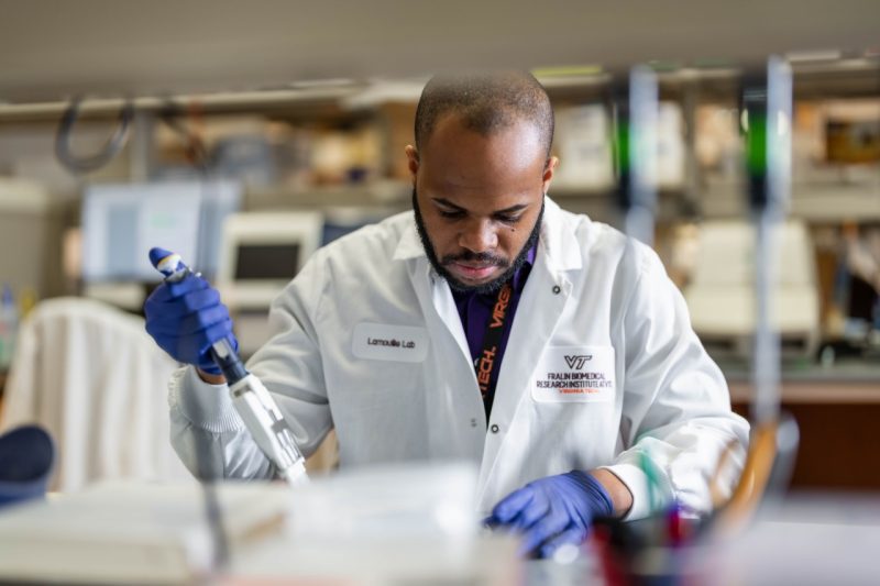 Man wearing white lab coat working in a scientific lab.