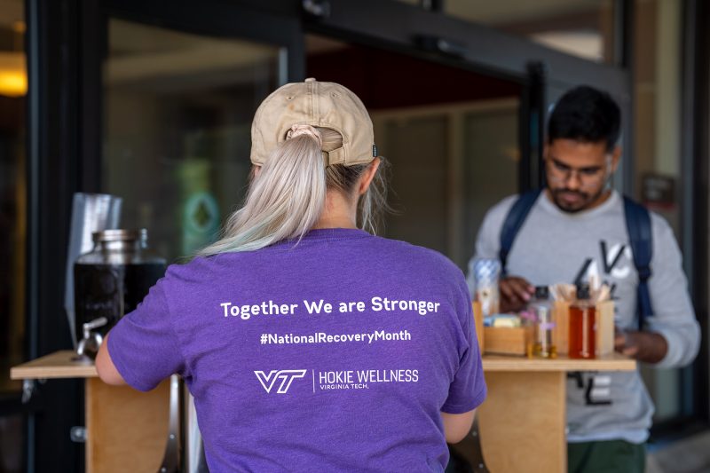 A person is seen from behind wearing a Virginia Tech Recovery Community T-shirt.