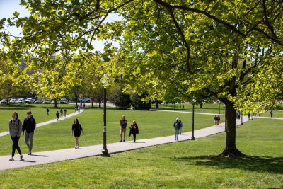 Students cross the Drillfield on a sunny day.