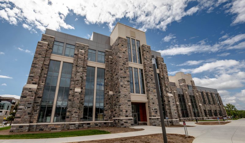 Grey Hokie Stone, glass, and precast concrete Hitt Hall on a sunny day.