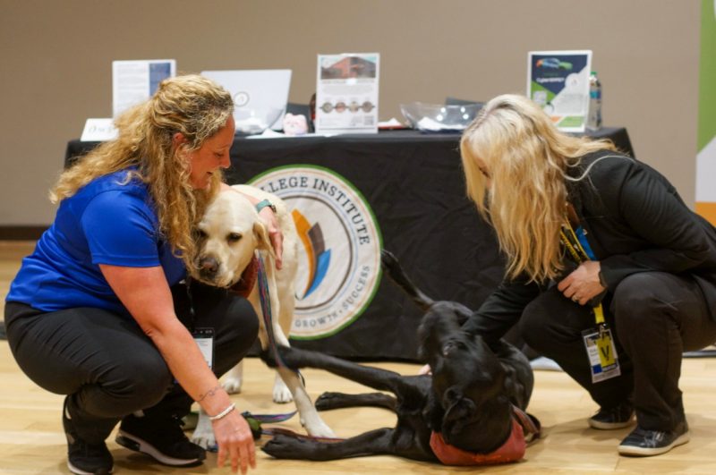 two adults hugging the VT therapy dogs