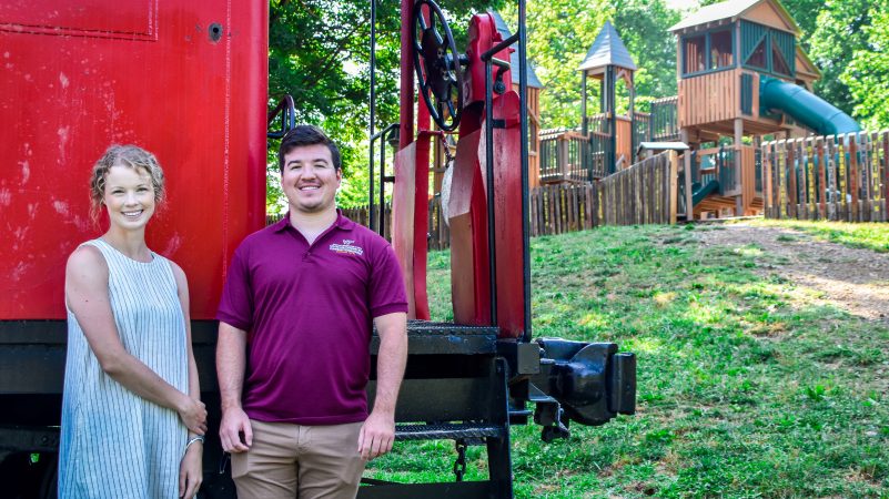 Economic development specialists Dylan Andrews and Ashley Posthumus pose for a picture in front of the caboose at Blacksburg Municipal Park.