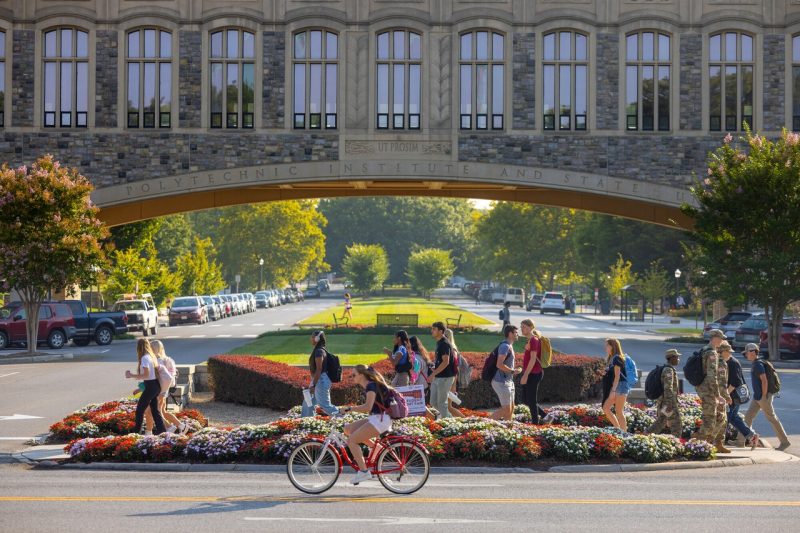 Students walk and bike in front of Torgersen Bridge.