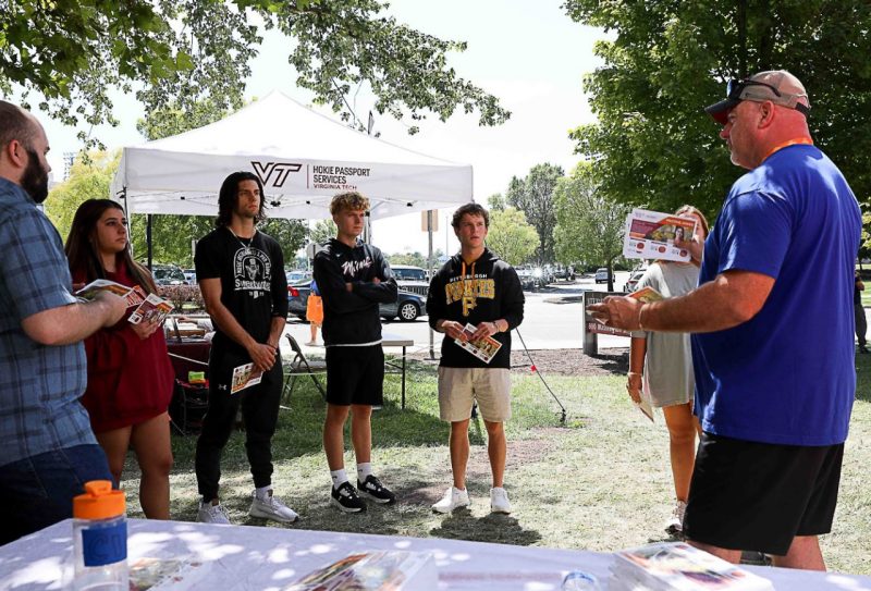 Clay Tate with Mail Services talks to a group of students at Information Station during move-in at Virginia Tech