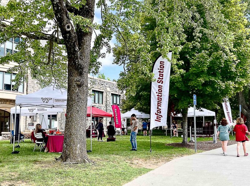 Several tents on the lawn of the Student Services Building as students walk around the Information Station at Virginia Tech