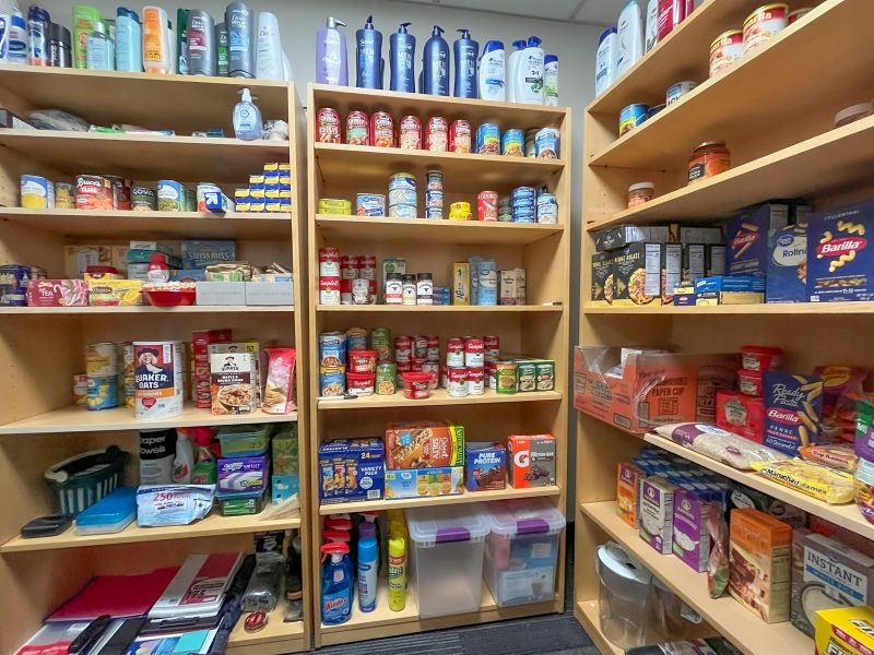 Shelves in the corps pantry stocked with colorful containers of food, personal hygiene items, and cleaning supplies.