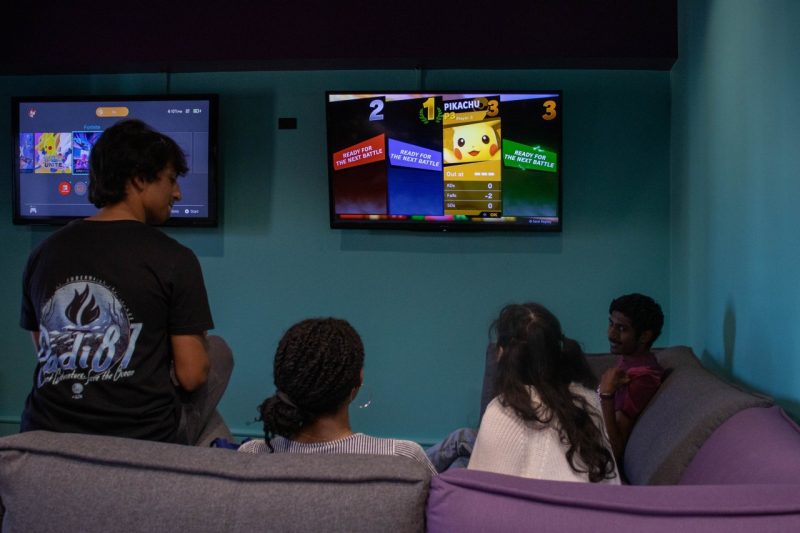 Students sit on couches and play video games in Gaming Studio.
