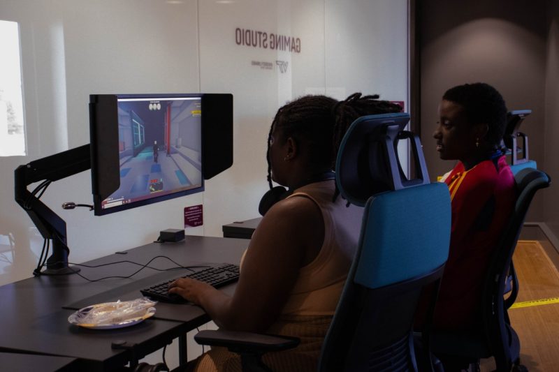 A student uses one of the high-powered gaming computers along a well-lit wall in the studio.