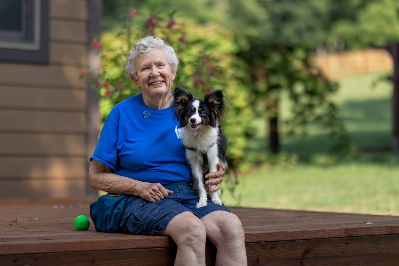 Sharon Harrell (at left) with her dog, Miryam sitting on a porch.
