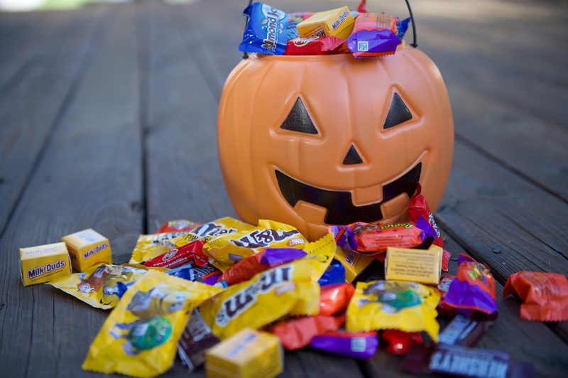 A plastic pumpkin is surrounded by candy.