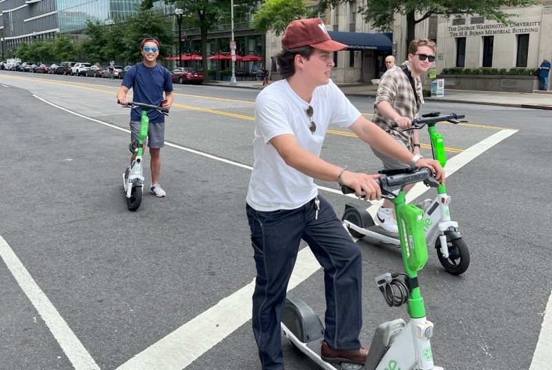 Students Riding Scooters Students riding e-scooters pause on a city street.