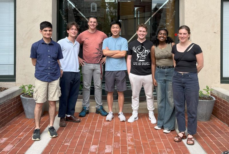 Scooter Research Team Seven students stand in front of the entrance of a building, posing for a photo.