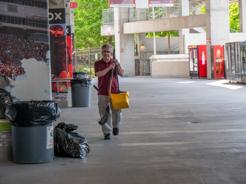 Gerald Jones walks on the concourse in Lane Stadium while holding a mop