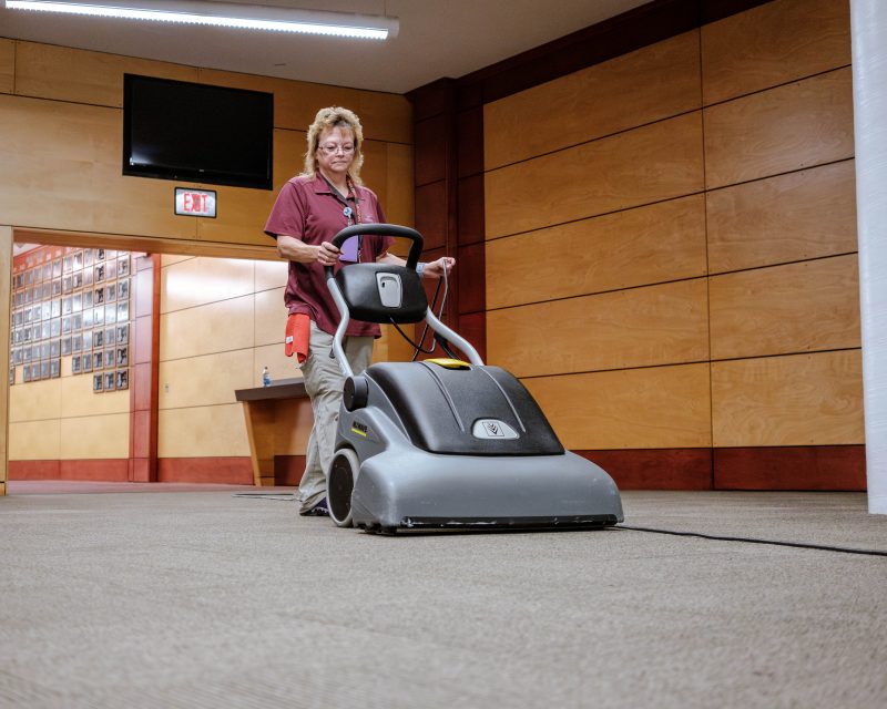 Patty Gillespie uses a large vacuum to clean the floors in Cassell Coliseum