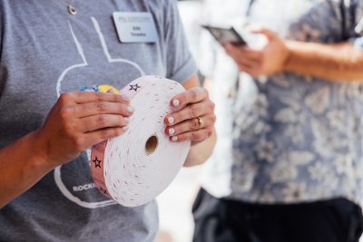 Hands hold a roll of pink tickets.